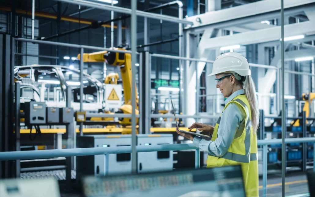 Automotive-Engineer-Wearing-Hard-Hat-Standing-Using-Laptop