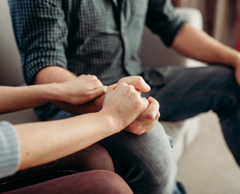Side view of people holding hands in therapy session